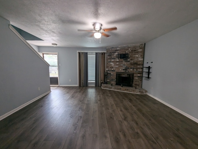 unfurnished living room with dark hardwood / wood-style floors, ceiling fan, a textured ceiling, and a brick fireplace