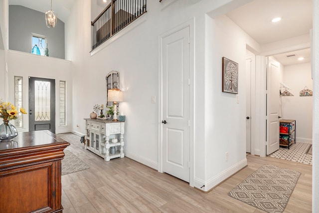 foyer featuring a towering ceiling and light wood-type flooring