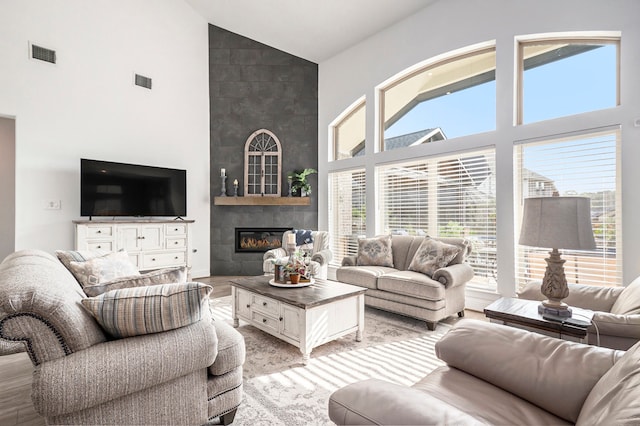 living room with light hardwood / wood-style flooring, high vaulted ceiling, and a tile fireplace