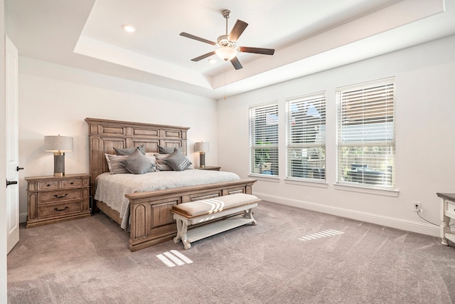 bedroom with carpet flooring, a tray ceiling, and ceiling fan