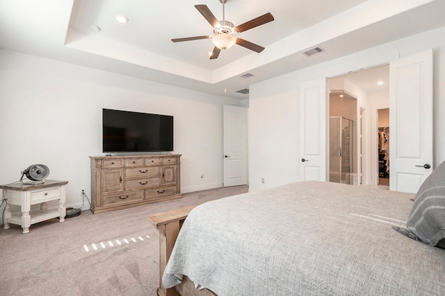 carpeted bedroom with a spacious closet, a raised ceiling, and ceiling fan