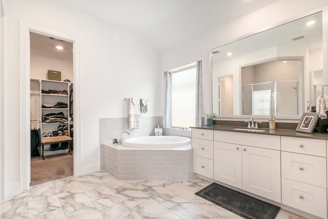 bathroom with vanity, separate shower and tub, and vaulted ceiling