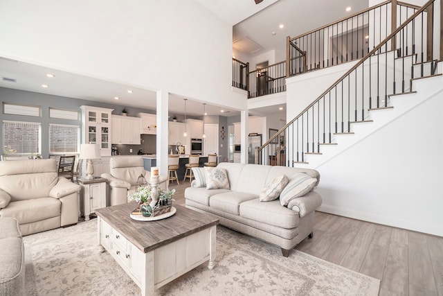 living room with a towering ceiling and light wood-type flooring