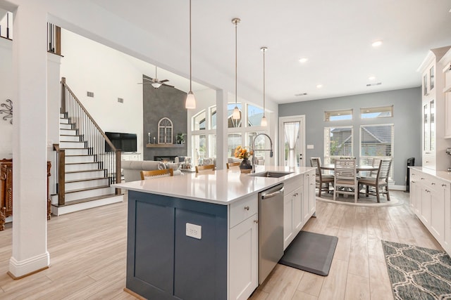 kitchen featuring white cabinets, a center island with sink, ceiling fan, stainless steel dishwasher, and sink