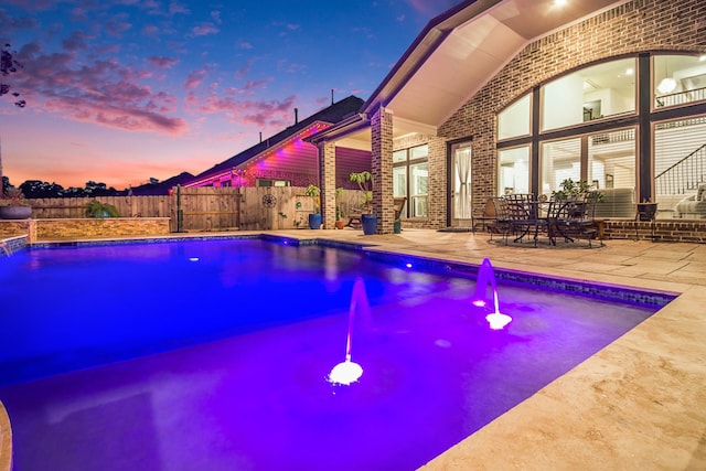 pool at dusk featuring a patio