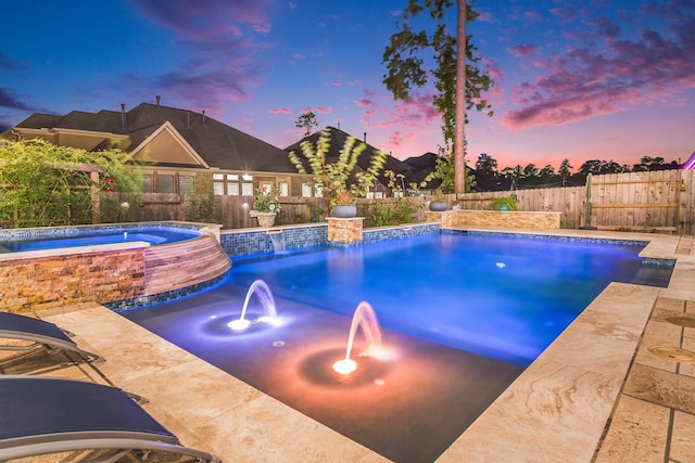 pool at dusk with an in ground hot tub and pool water feature