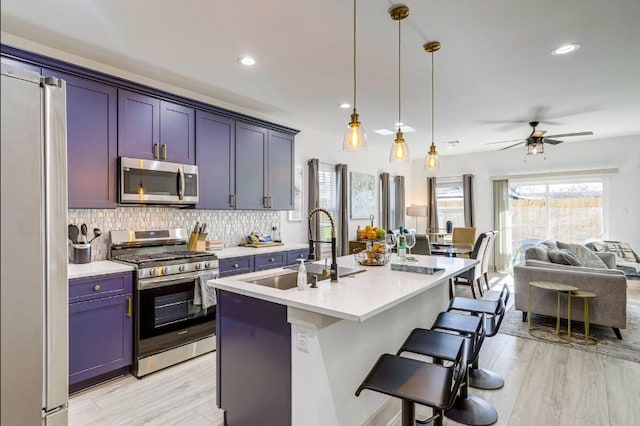 kitchen featuring a center island with sink, a kitchen bar, light hardwood / wood-style flooring, sink, and stainless steel appliances