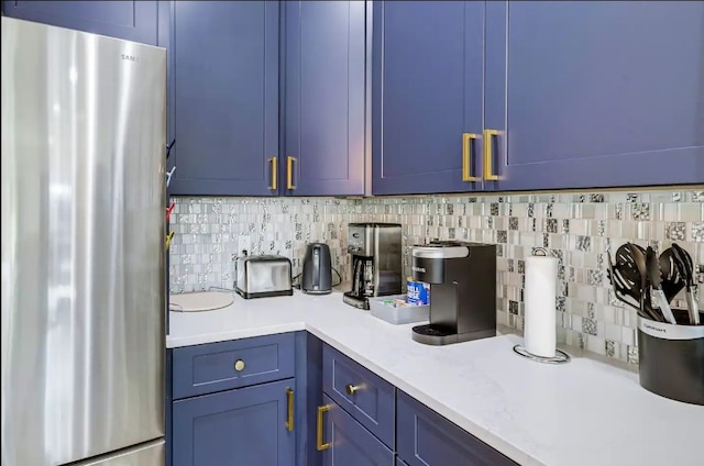 kitchen featuring blue cabinets, stainless steel fridge, and tasteful backsplash