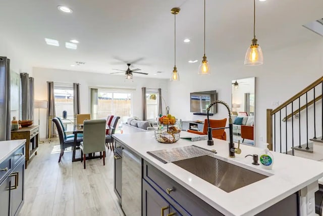 kitchen featuring ceiling fan, a kitchen island, light hardwood / wood-style flooring, sink, and decorative light fixtures