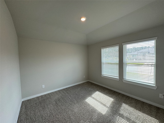 carpeted spare room with vaulted ceiling