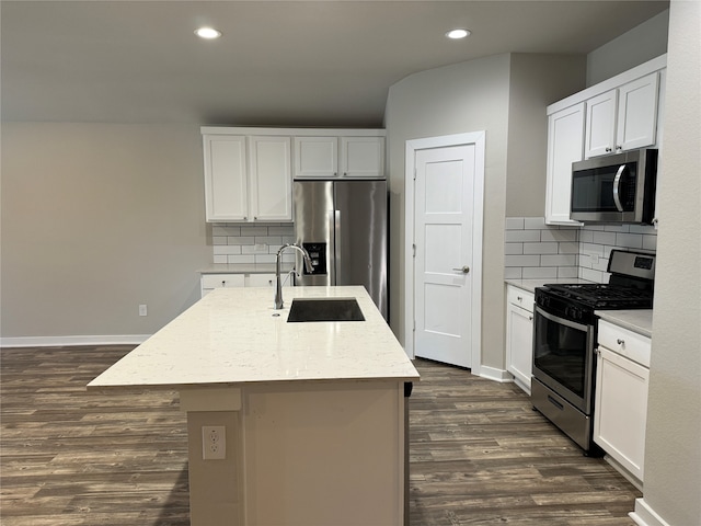 kitchen with sink, appliances with stainless steel finishes, a kitchen island with sink, tasteful backsplash, and white cabinets