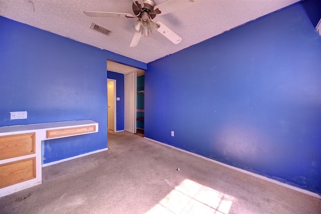 empty room featuring a textured ceiling, carpet, and ceiling fan