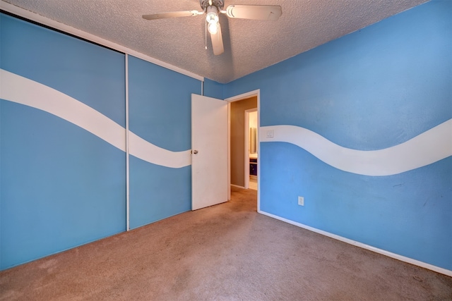 unfurnished bedroom with carpet flooring, a textured ceiling, a closet, and ceiling fan