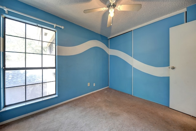 carpeted empty room with ceiling fan and a textured ceiling