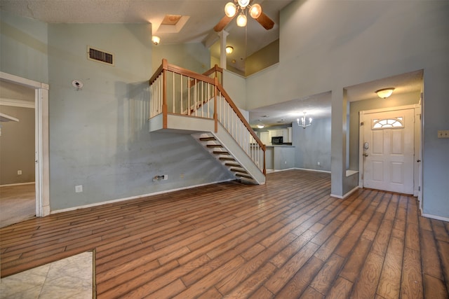 foyer entrance featuring hardwood / wood-style flooring, high vaulted ceiling, a textured ceiling, and ceiling fan with notable chandelier