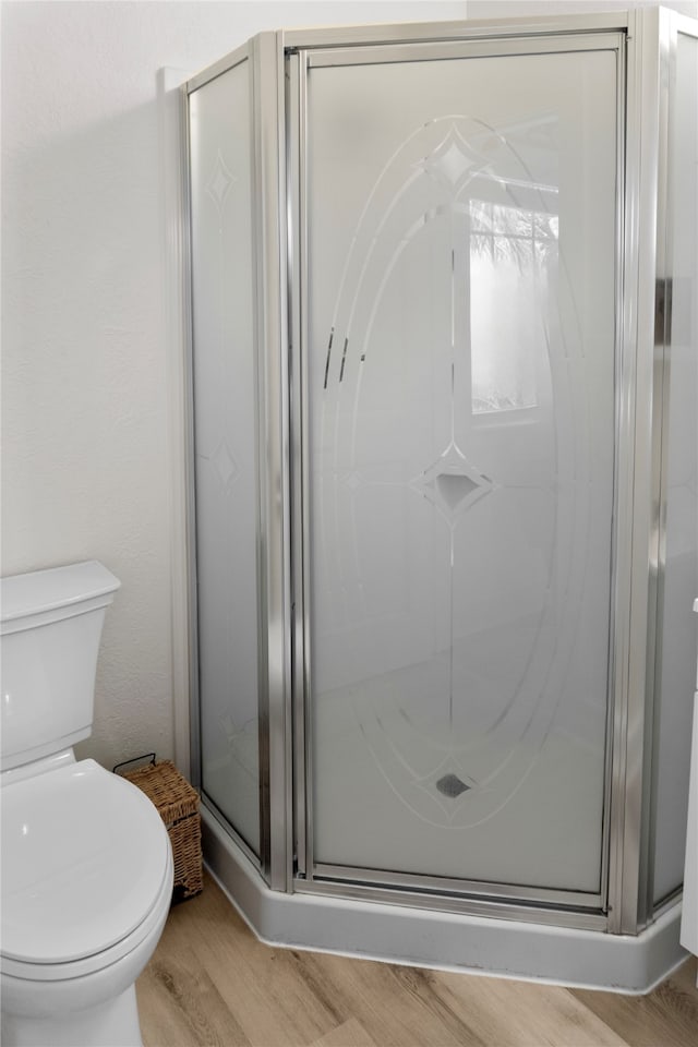 bathroom with toilet, an enclosed shower, and hardwood / wood-style flooring