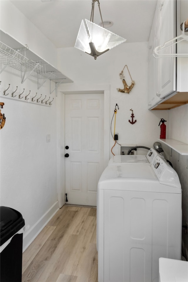 washroom with cabinets, light wood-type flooring, and washing machine and clothes dryer