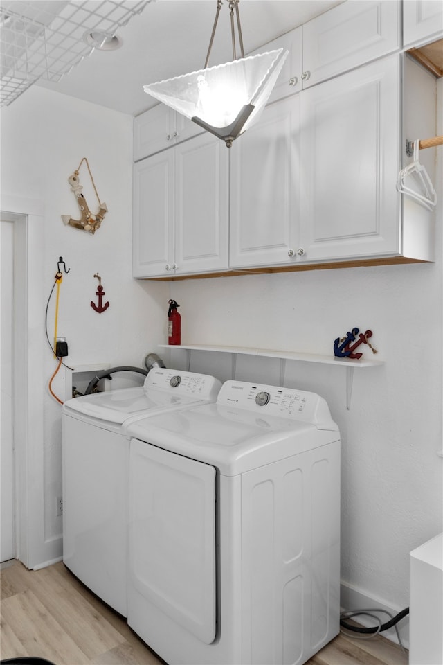 washroom with cabinets, light wood-type flooring, and washing machine and clothes dryer