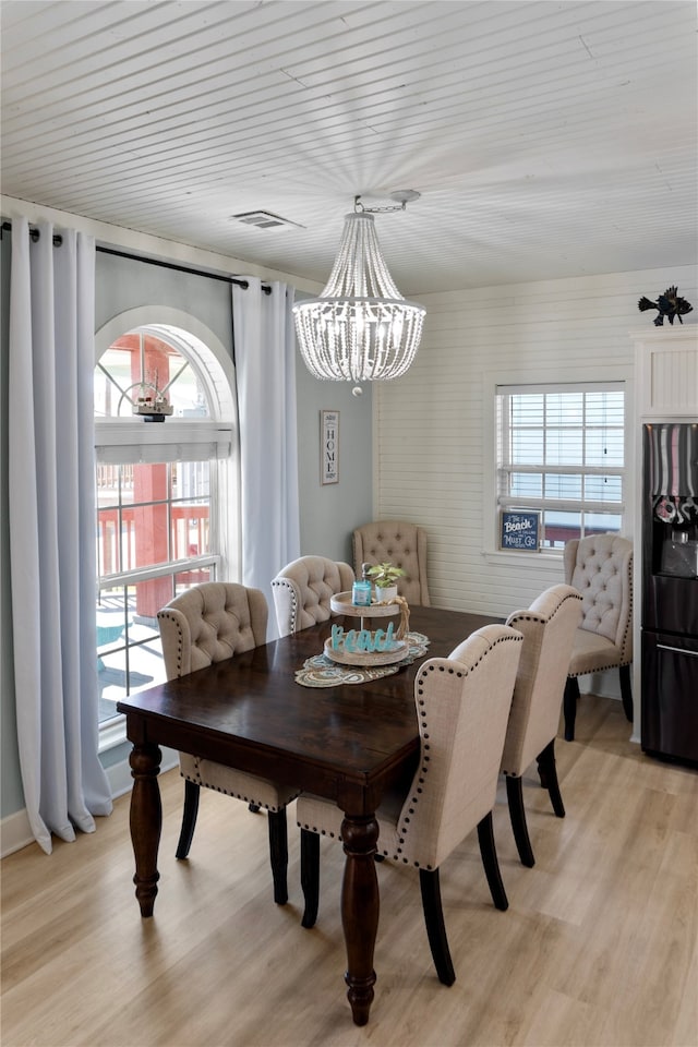 dining space featuring a notable chandelier, light hardwood / wood-style floors, and wooden ceiling