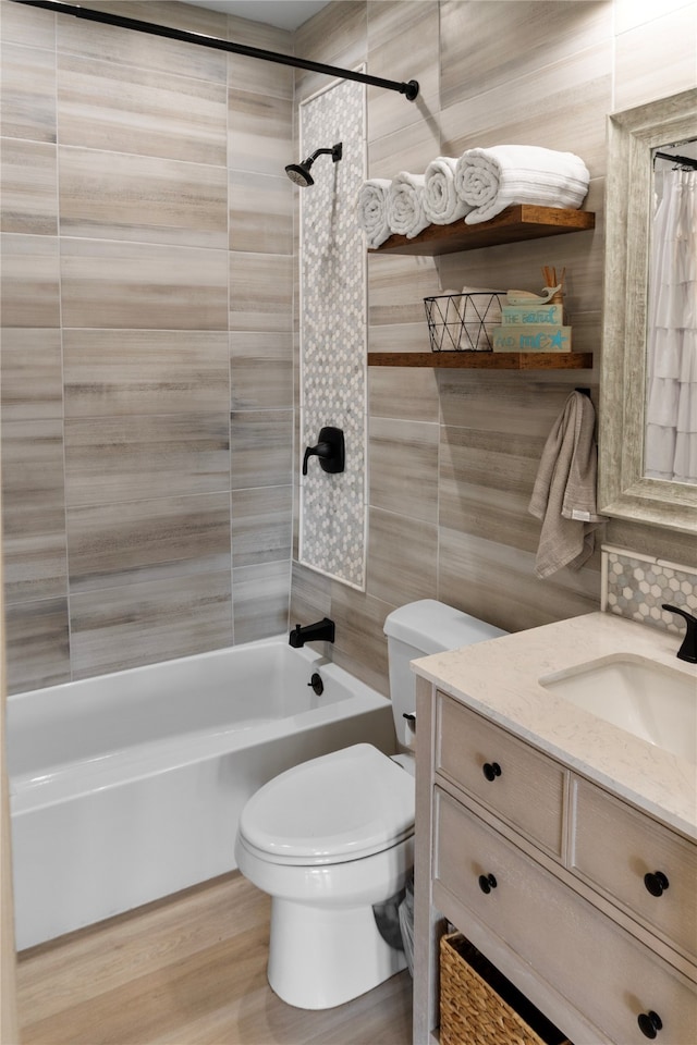 full bathroom featuring wood-type flooring, toilet, shower / bath combo with shower curtain, tile walls, and vanity