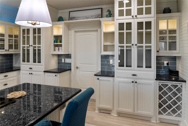 kitchen with white cabinetry, light hardwood / wood-style flooring, decorative backsplash, and dark stone counters