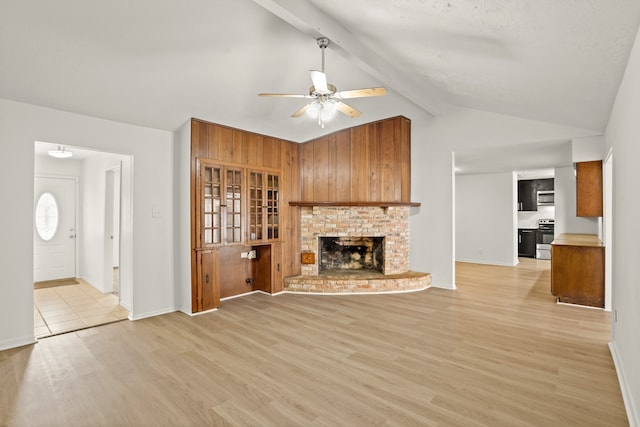 unfurnished living room with light hardwood / wood-style flooring, vaulted ceiling with beams, a fireplace, and ceiling fan