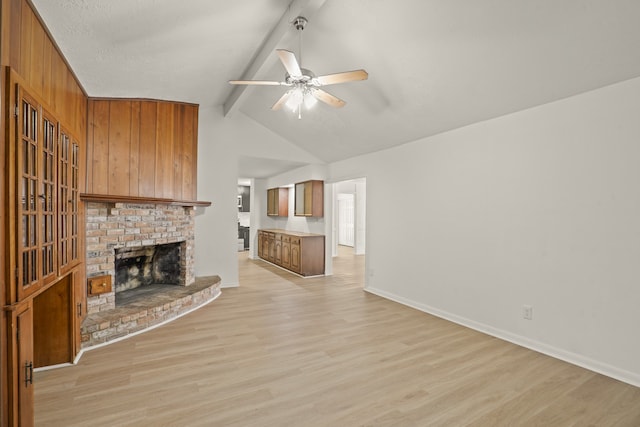 unfurnished living room with light wood-type flooring, lofted ceiling with beams, a brick fireplace, and ceiling fan