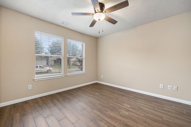 empty room featuring ceiling fan, a textured ceiling, and dark hardwood / wood-style flooring