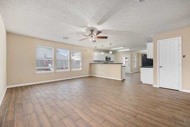 unfurnished living room featuring a textured ceiling, light wood-type flooring, and ceiling fan