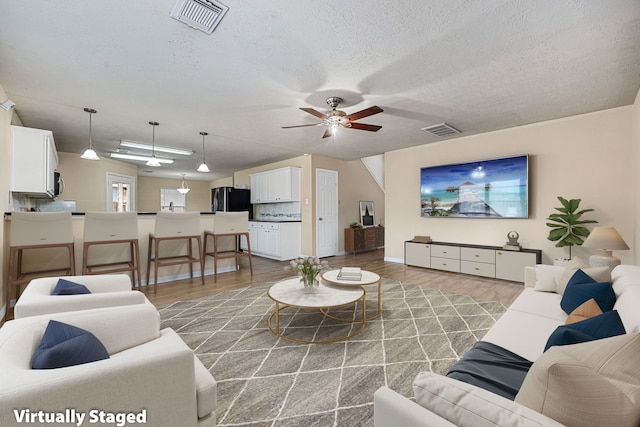 living room featuring hardwood / wood-style floors, a textured ceiling, and ceiling fan