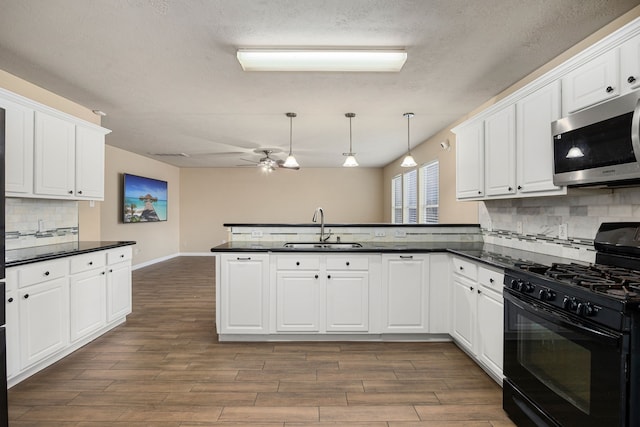 kitchen featuring sink, white cabinetry, kitchen peninsula, and black gas range oven