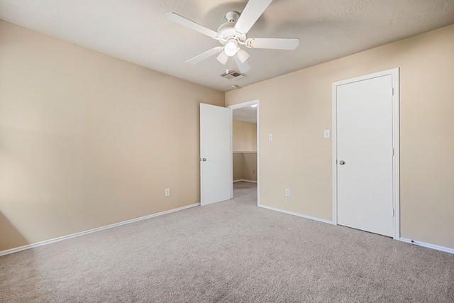 carpeted empty room with ceiling fan and a textured ceiling