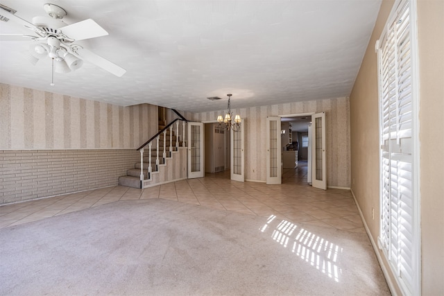 unfurnished living room featuring french doors, light tile patterned flooring, and ceiling fan with notable chandelier