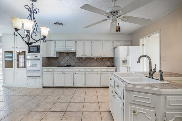 kitchen with sink, pendant lighting, light tile patterned floors, white appliances, and tasteful backsplash