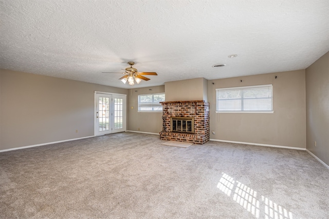 unfurnished living room featuring carpet flooring, a fireplace, french doors, a textured ceiling, and ceiling fan