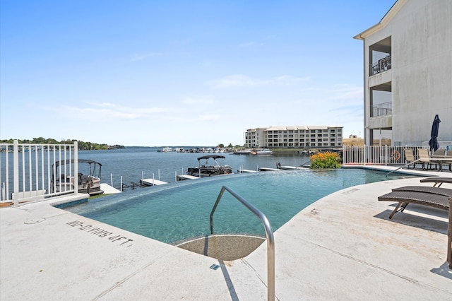 view of swimming pool featuring a water view, a dock, and a patio area