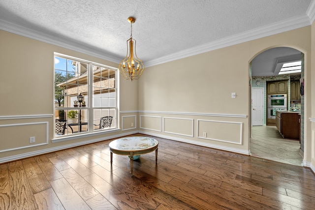 interior space featuring crown molding, a textured ceiling, an inviting chandelier, and hardwood / wood-style floors