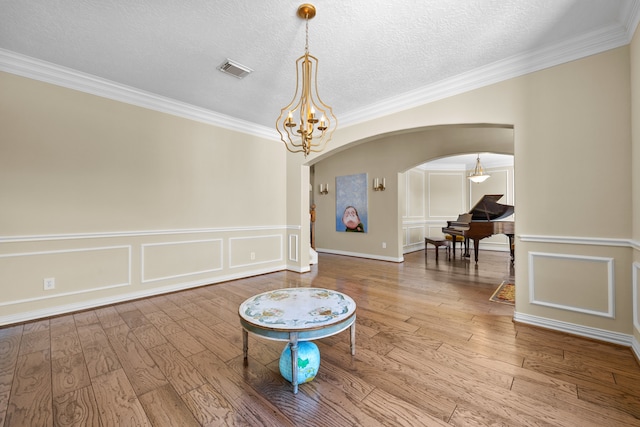 unfurnished room featuring ornamental molding, hardwood / wood-style floors, a notable chandelier, and a textured ceiling