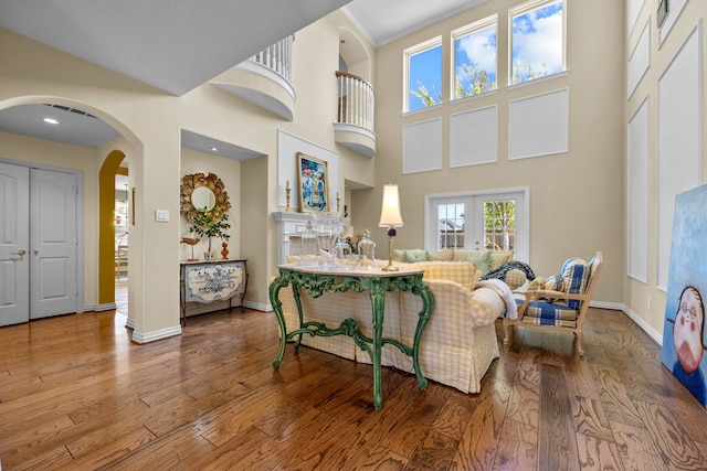 living room with wood-type flooring and a towering ceiling