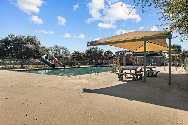 view of pool with a water slide and a patio area