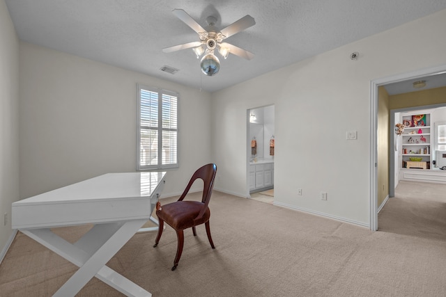 carpeted office with a textured ceiling and ceiling fan