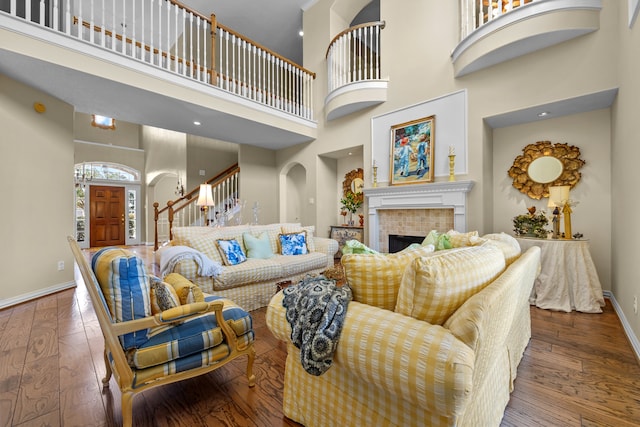 living room with a tiled fireplace, hardwood / wood-style flooring, and a towering ceiling