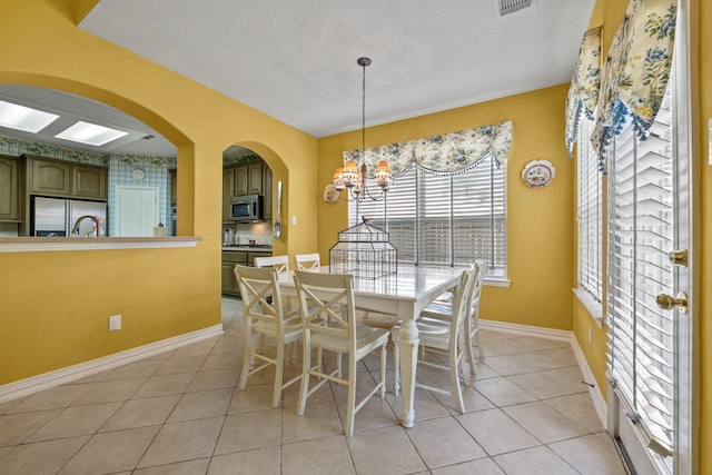 tiled dining room with a textured ceiling and an inviting chandelier