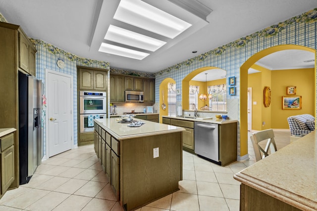 kitchen featuring light tile patterned flooring, a center island, hanging light fixtures, stainless steel appliances, and ornamental molding