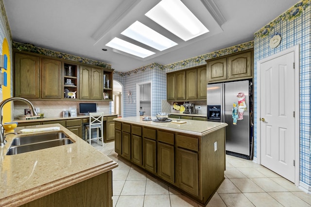 kitchen featuring sink, dark brown cabinets, a center island, stainless steel fridge, and light tile patterned floors