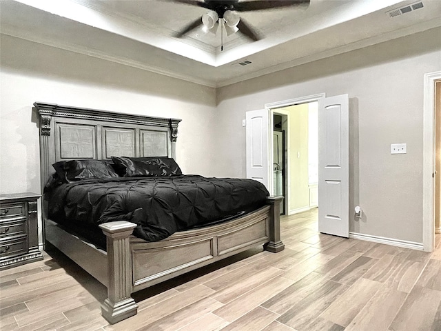 bedroom with ornamental molding, light hardwood / wood-style floors, ceiling fan, and a raised ceiling