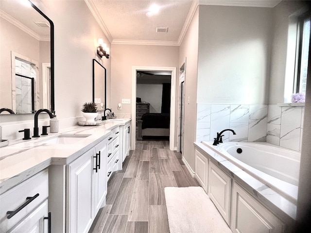 bathroom with a textured ceiling, vanity, a tub, and crown molding