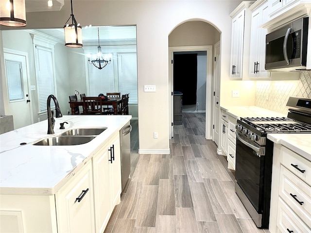 kitchen featuring a chandelier, sink, white cabinetry, appliances with stainless steel finishes, and decorative light fixtures