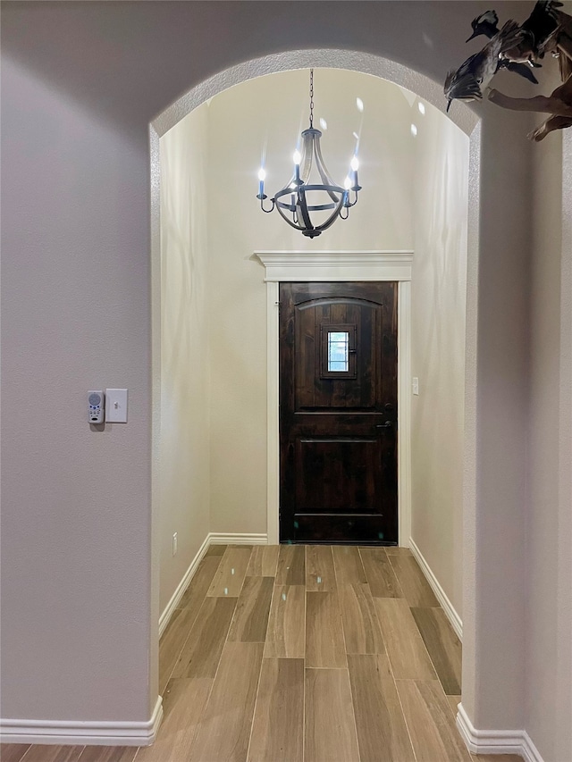 foyer entrance with light hardwood / wood-style floors and an inviting chandelier