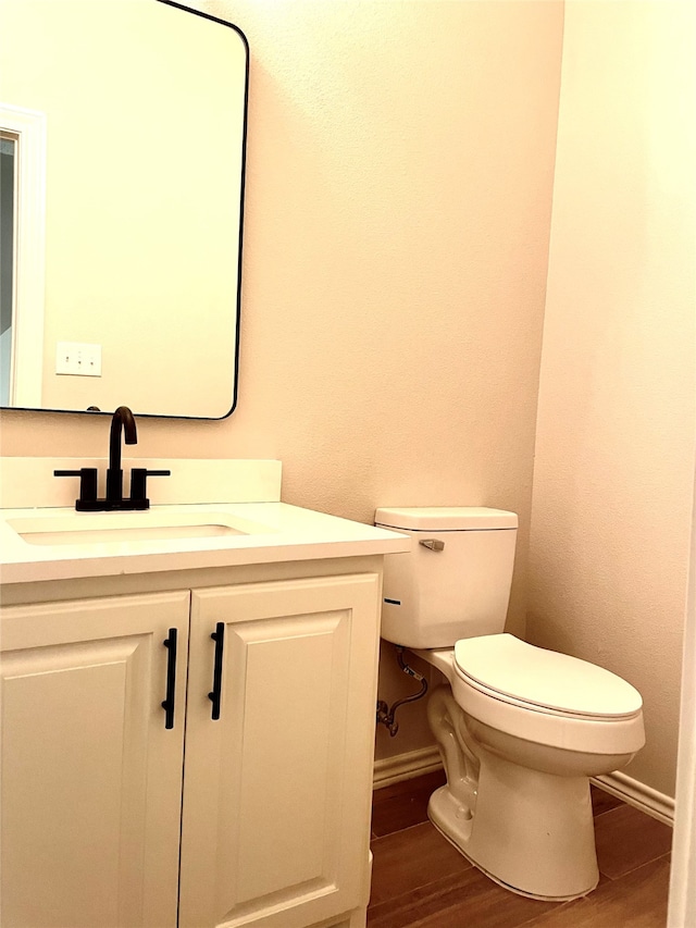 bathroom featuring toilet, vanity, and hardwood / wood-style floors